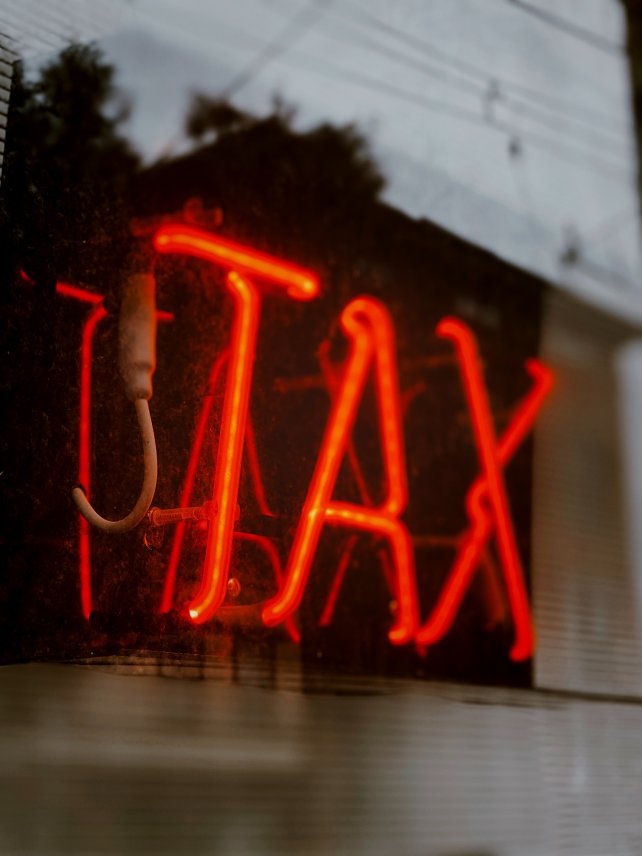 Red neon sign that spells out TAX
